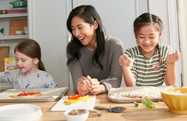 Diverse family making pizzas using almond flour baking mix Pizza Dough