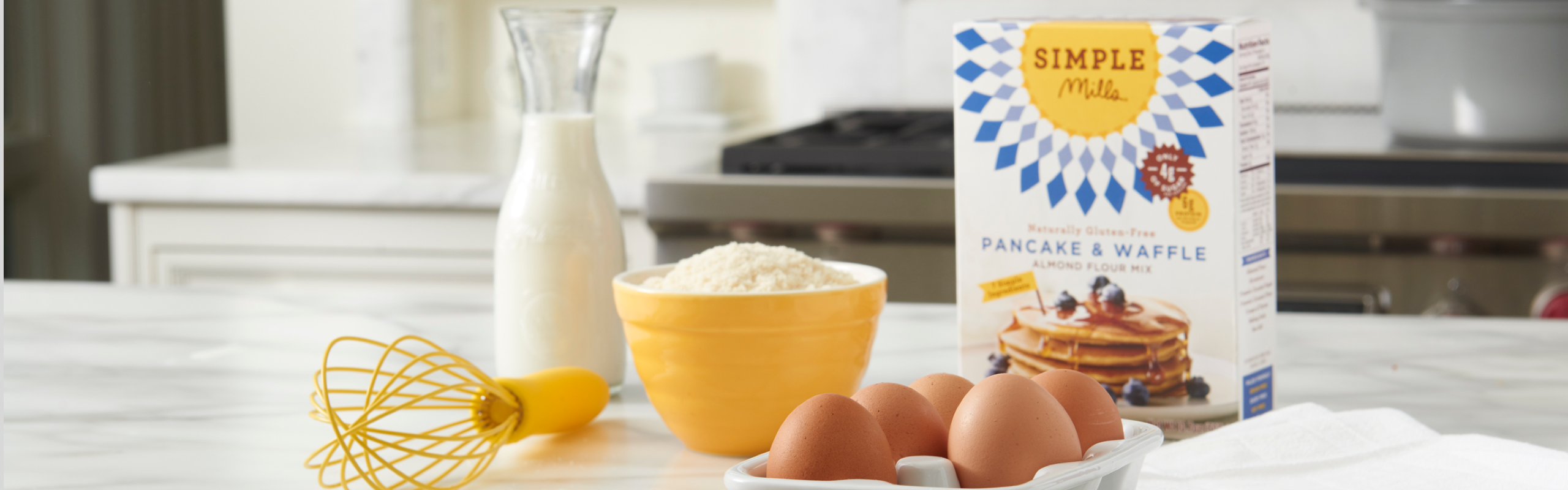 Woman holding a basket fillet with groceries including Simple Mills Almond Flour Baking Mixes