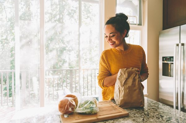 girl-cooking-in-kitchen-yellow-sweater.jpg Woman in yellow sweater smiling, excited to make recipes