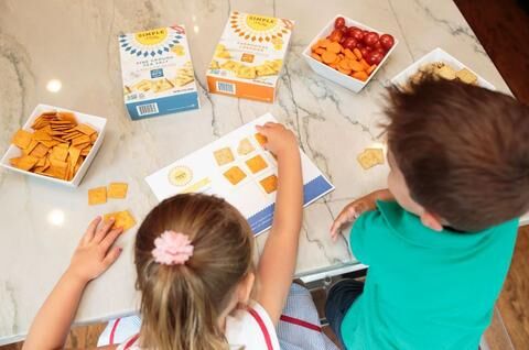 Young girl and boy playing tic tac toe using Simple Mills almond flour crackers