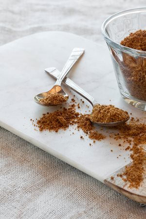 Bowl and spoon fulls of coconut sugar to be used as a sweetner in a recipe