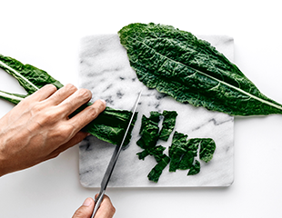 Fresh Kale being cut on white marble cutting board