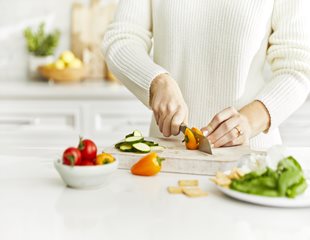 Women cutting fresh vegetables to incorporate in her recipes