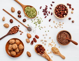 Arial view of whole and ground nuts in wooden bowls and wooden spoons of varying sizes